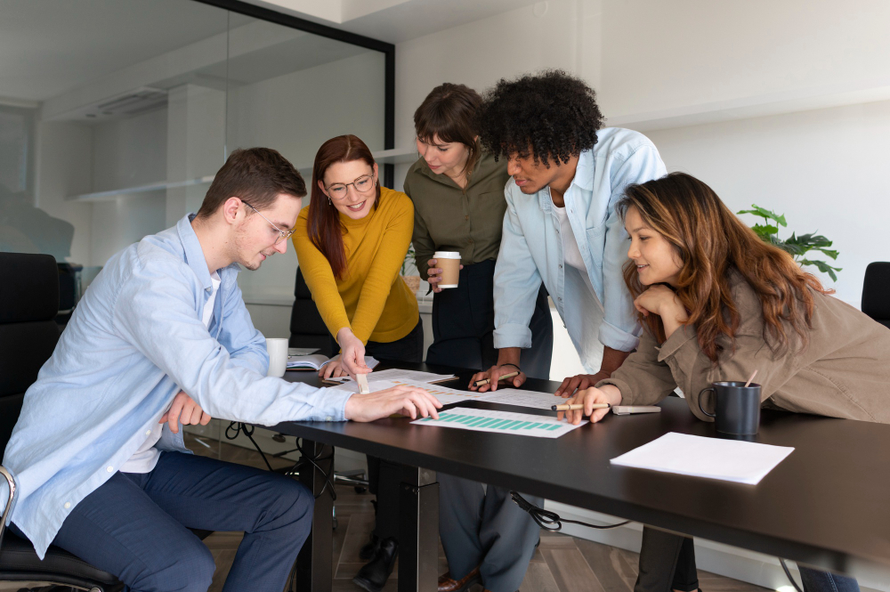  A diverse team gathered around a meeting table, actively discussing documents and sharing ideas, demonstrating collaboration, inclusion, and team psychological safety.