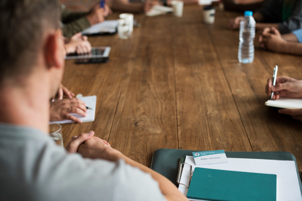 Professionals with notebooks seated around a wooden conference table, collaborating on a change management strategy