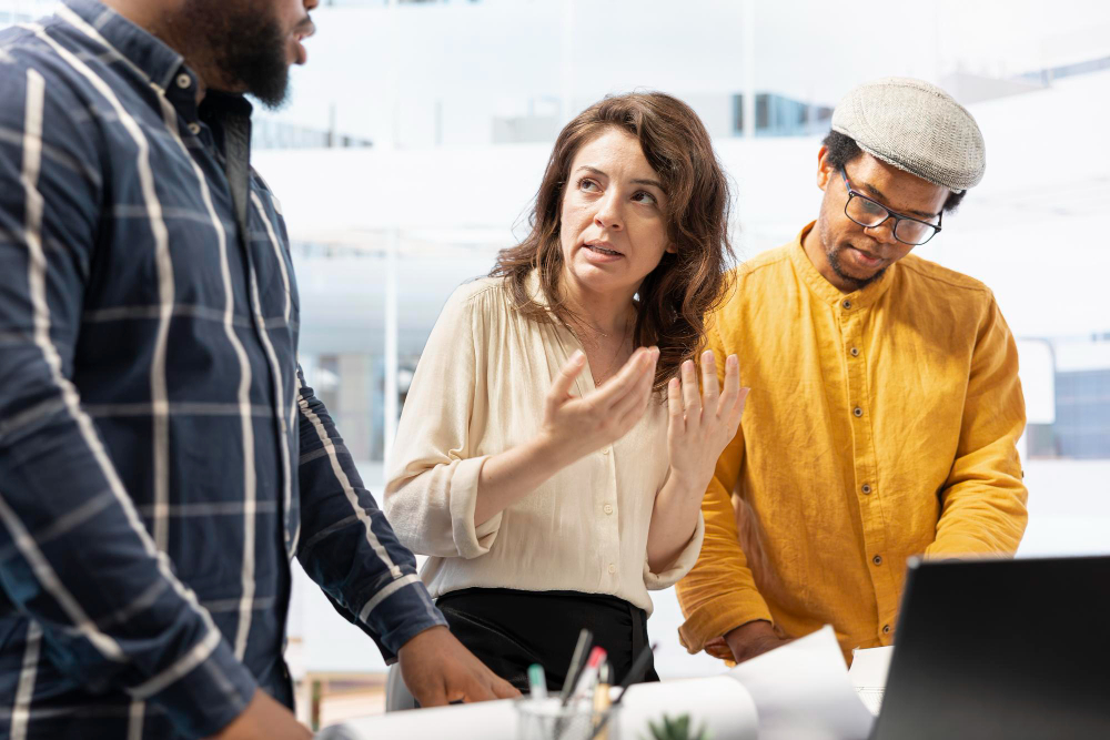 Three colleagues having a serious discussion over a laptop, illustrating the complex reality of executing new workflows