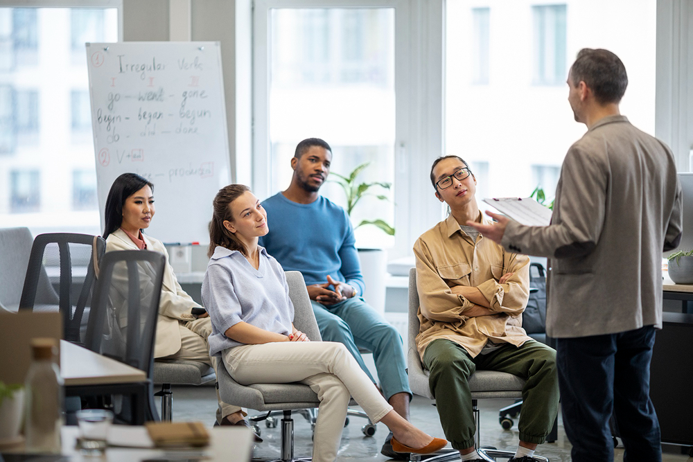A male instructor presenting to a diverse group of seated employees during a workplace training session